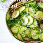 Pin Image: A bowl of asian cucumber salad with red onions with text overlaid