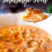Pin Image: Close-up of creamy sausage soup with pasta on a spoon with text overlaid