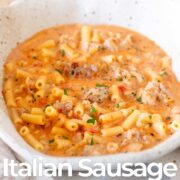 Pin Image: Creamy Italian sausage pasta soup in a bowl with text overlaid.