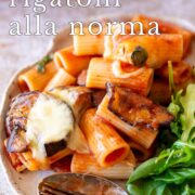 Pin Image: Plate of baked rigatoni alla Norma with side salad with text overlaid