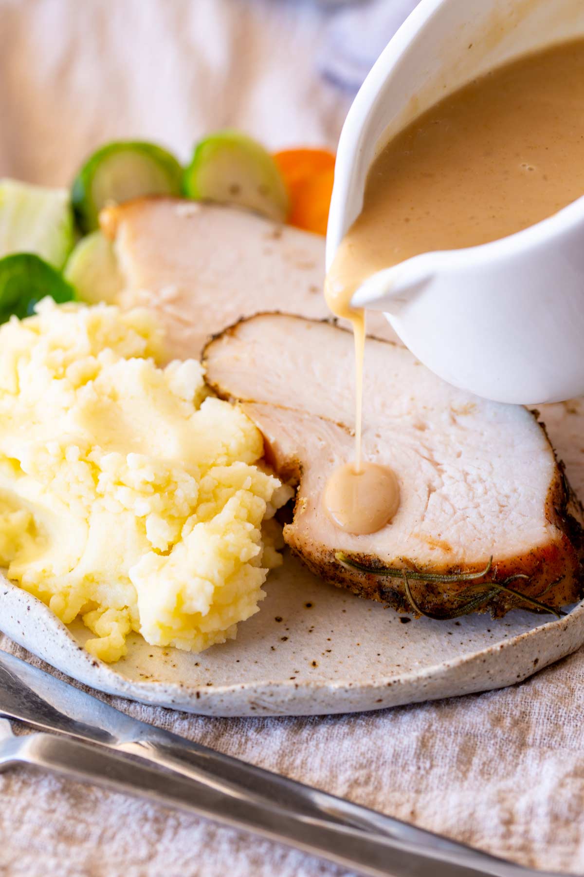 gravy being poured over a plate of turkey and mashed potato