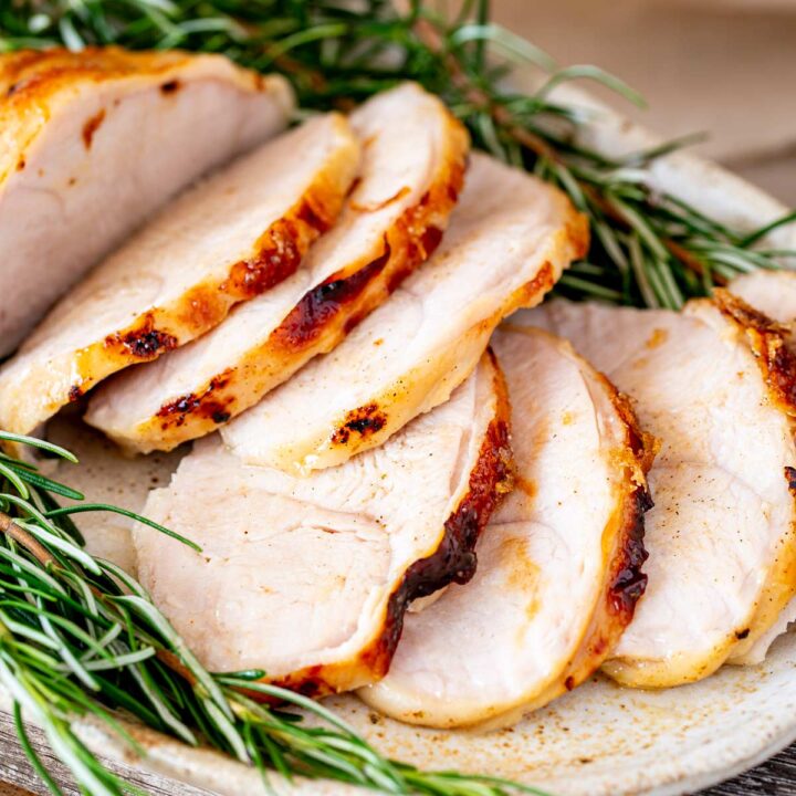Slices of roasted turkey breast shown close up with visible herbs and a natural backdrop.