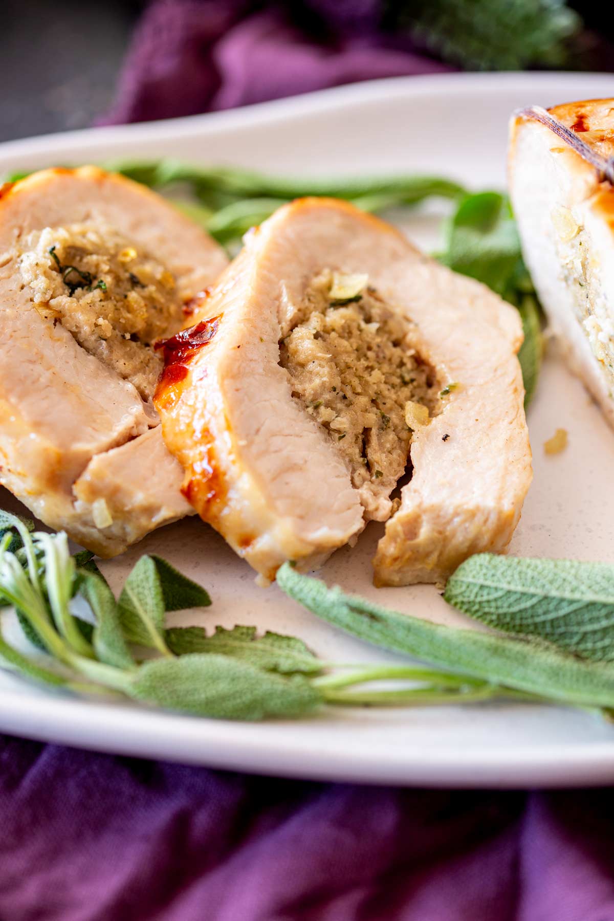 Sliced turkey breast showcasing the sage and onion stuffing, surrounded by a festive tablescape and rustic napkins.