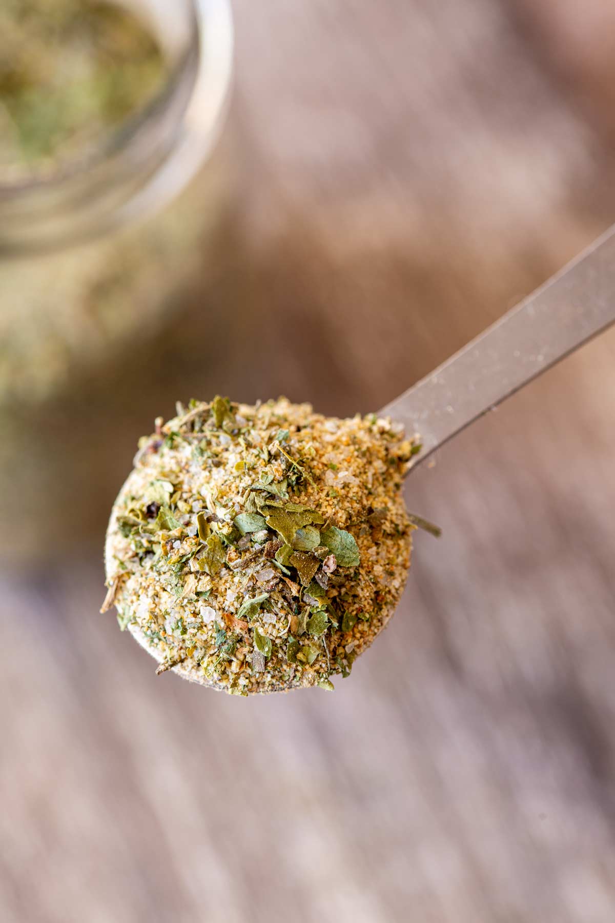 overhead of a spoonful of seasoning, you can see flecks of green and salt in the mixture