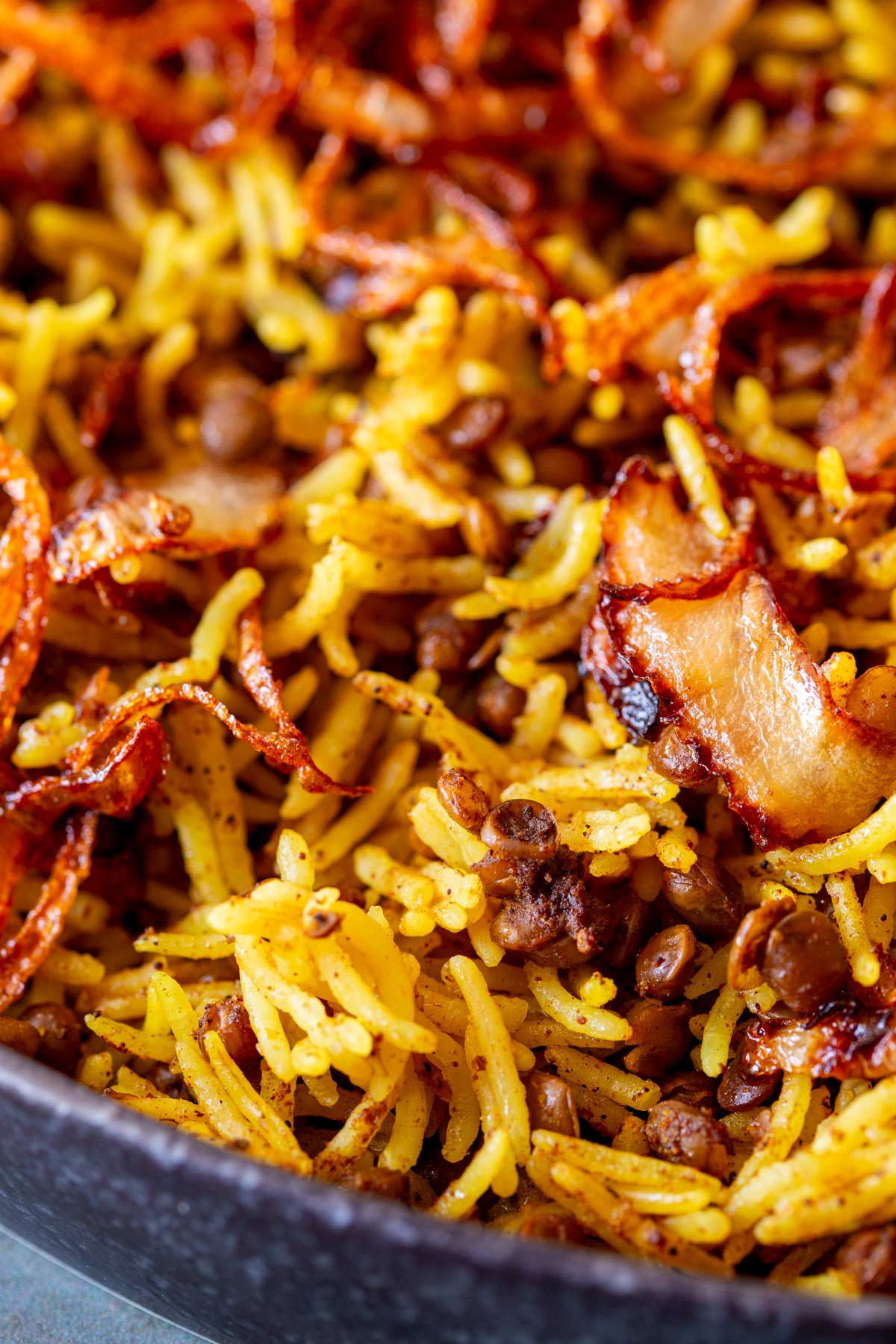 A detailed close-up of Mejadra, highlighting the fluffy, spiced rice and lentils, with crispy, golden-brown fried onions