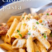 Pin Image: Creamy chicken and chorizo pasta in a shallow bowl with text overlaid.