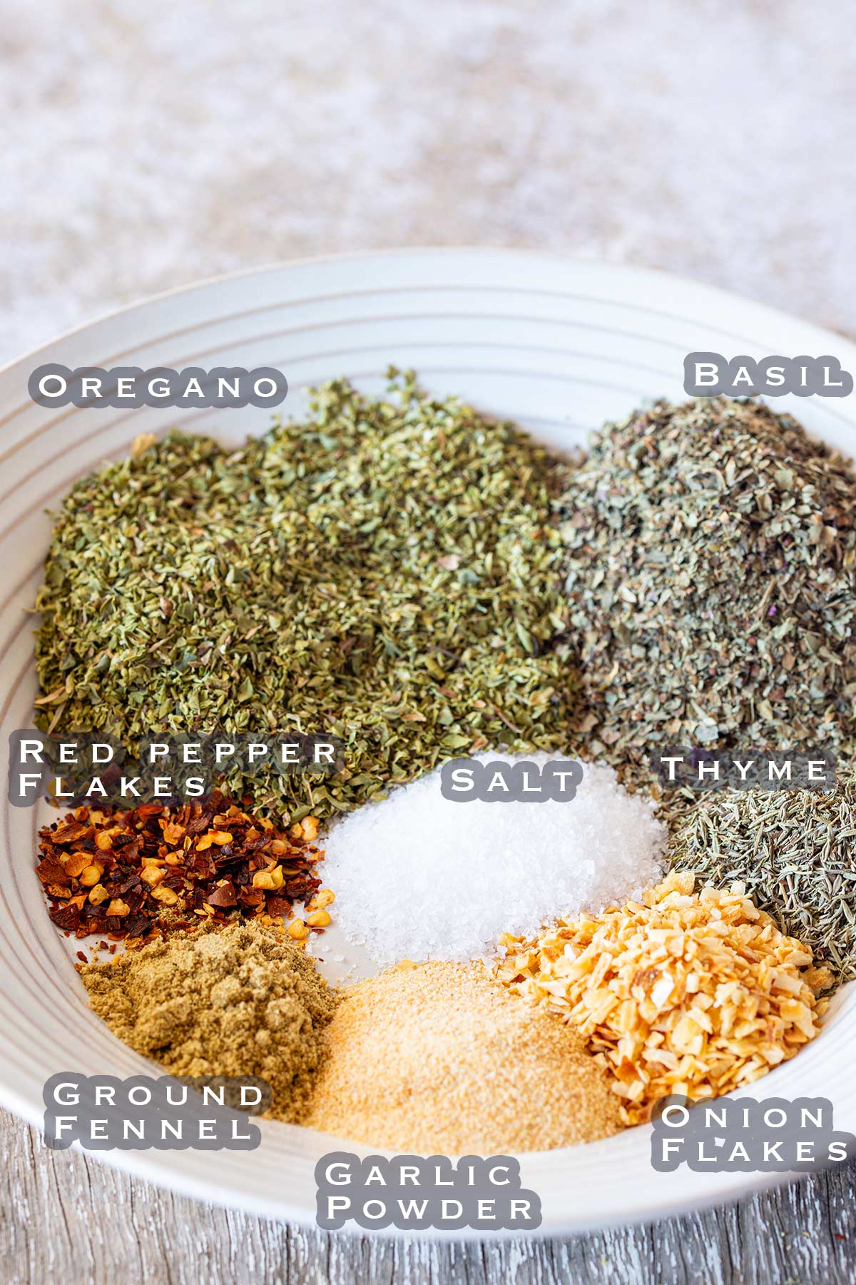 a bowl filled with labeled herbs and spices ready to make a seasoning blend