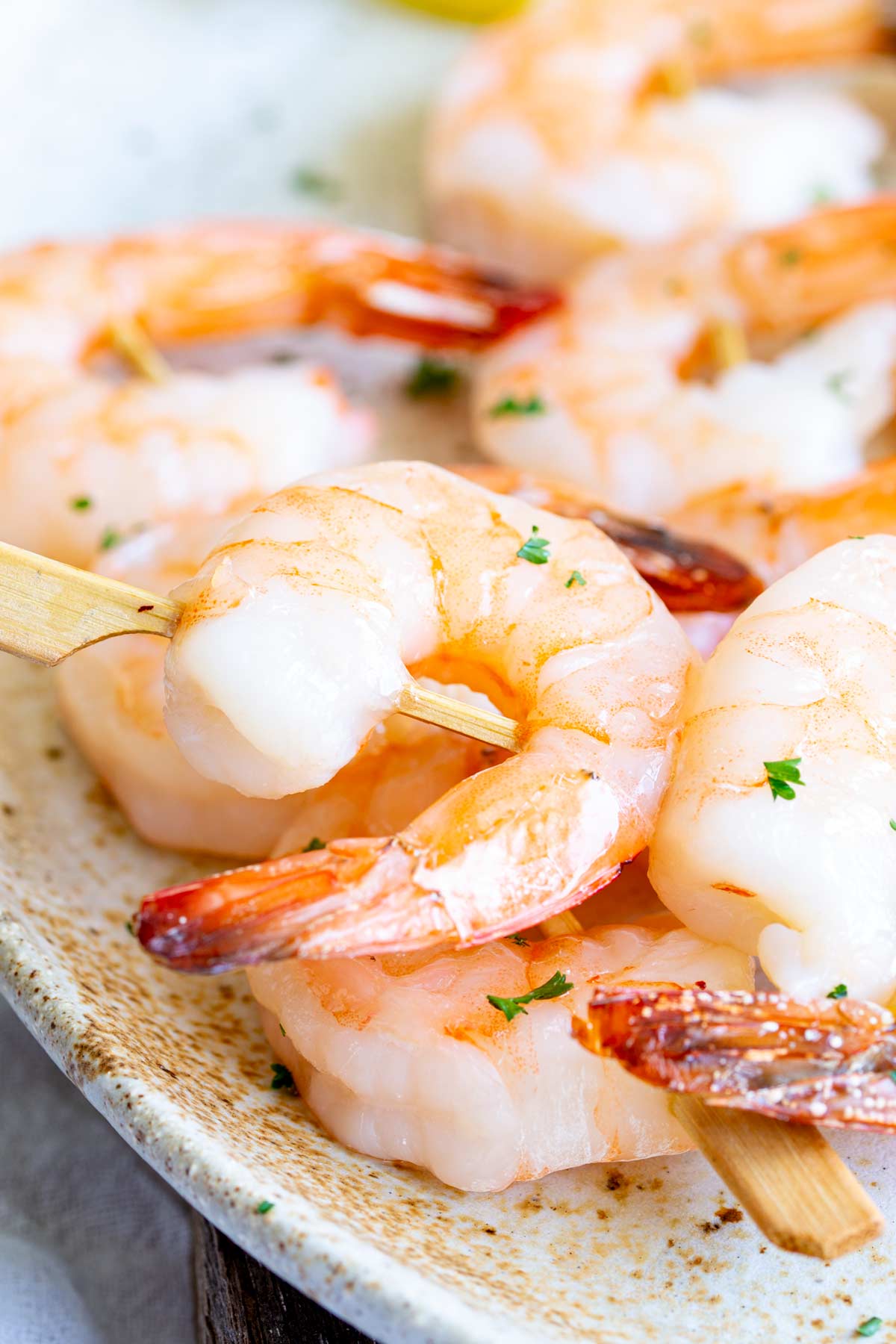 close up of shrimp skewers on a rustic plate with parsley garnish