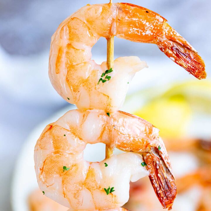 super close up of two roasted shrimp on a skewer
