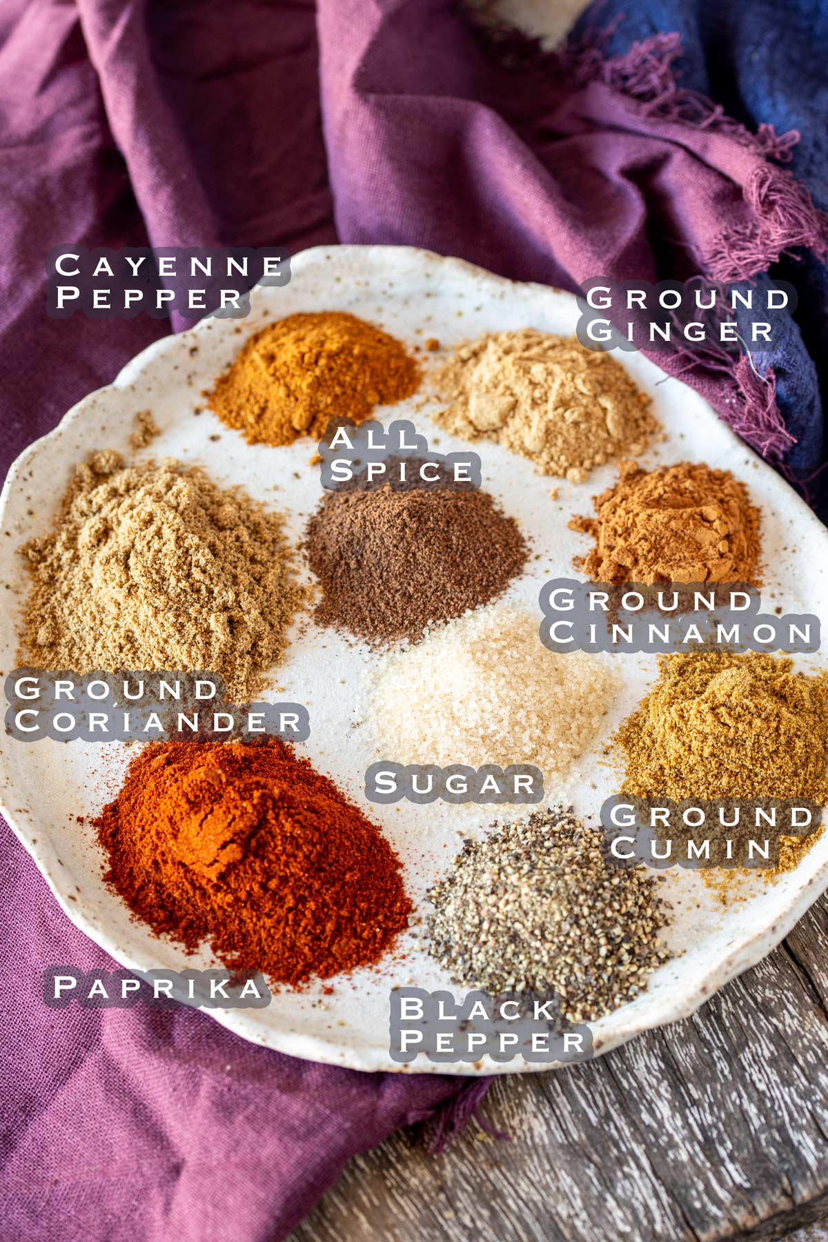 all the spices needed to make the moroccan seasoning, piled up on a rustic plate