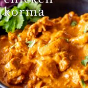 Pin Image: Close-up of golden Chicken Korma in black bowl with text overlaid