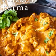 Pin Image:Chicken Korma in black bowl with rice and bread in the background with text overlaid