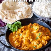 Pin Image: dark bowl filled with golden Chicken Korma, with roti and fluffy white rice with text overlaid