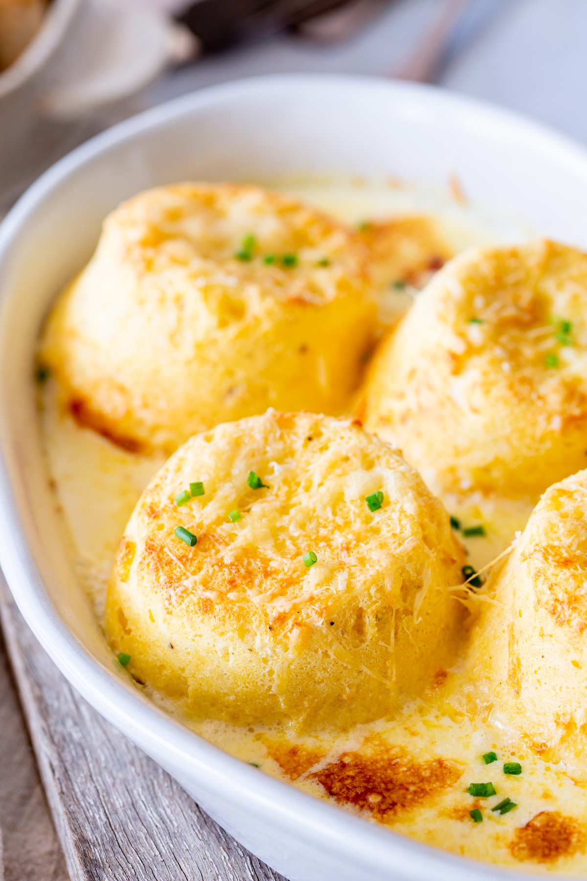 Four soufflés in rustic white baking dish on a wooden board