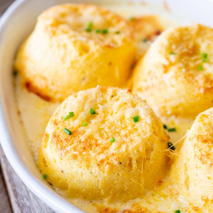 Close-up of golden twice baked cheese soufflés in a white baking dish