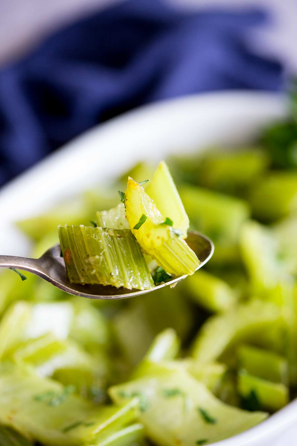 3 slices of celery on a metal spoon with the serving dish in the background