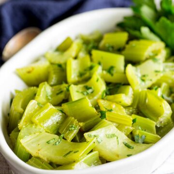 close up of a bowl of braised celery showing how it has softened and colored while cooking
