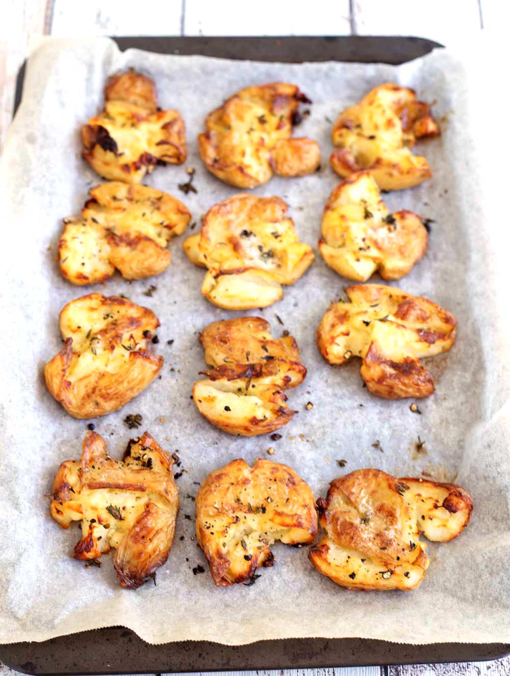 overhead shot showing 12 cooked crispy potatoes on a baking sheet