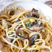 Pin Image: Cream bowl of pasta with mushrooms and leeks with text overlaid
