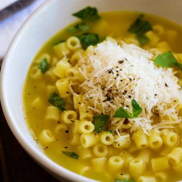 square image of small pasta shape in a bowl of buttery broth