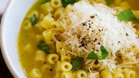 square image of small pasta shape in a bowl of buttery broth
