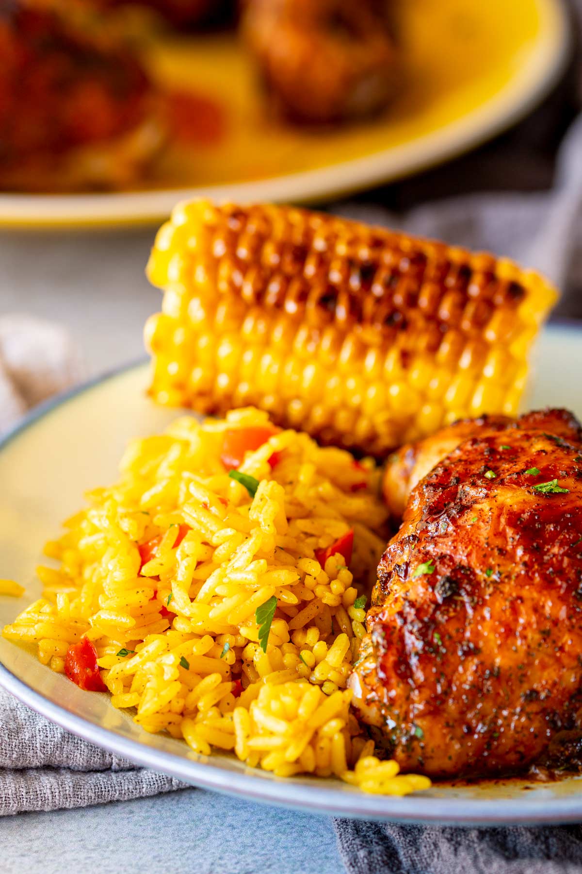 Fluffy golden rice served alongside charred peri-peri chicken and corn, creating a colorful plate