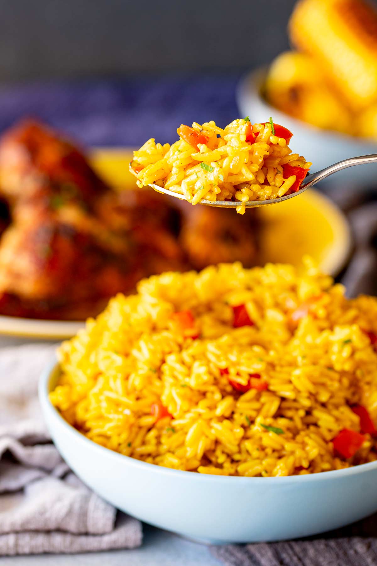 a spoon lifting yellow rice with bolts of bell pepper from a blue bowl