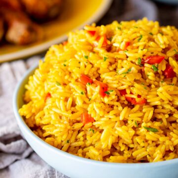 Close-up of golden rice with bits of onions and bell peppers mixed through it.