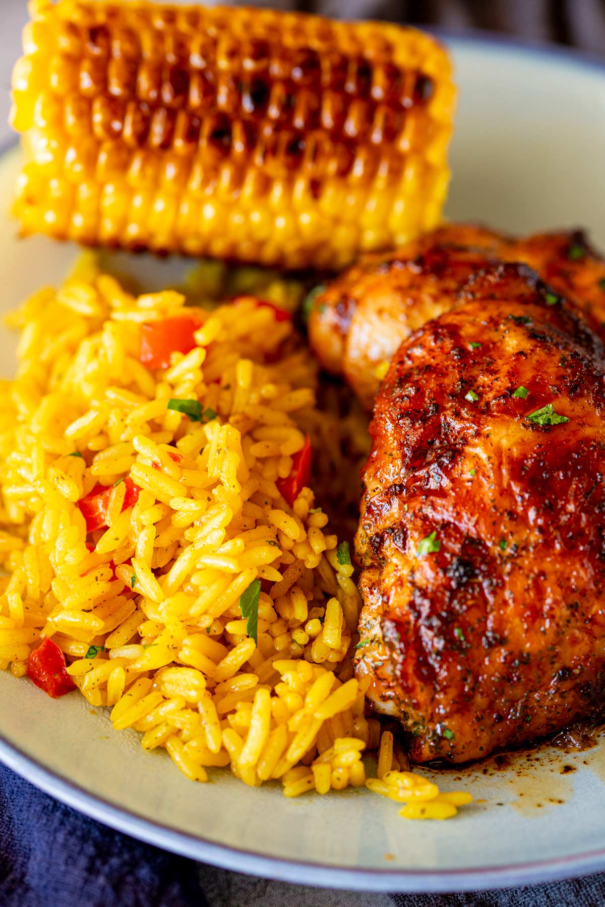 Portuguese rice plated on a light blue dish with peri-peri chicken and grilled corn on the side