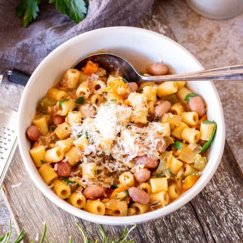 close up of a bowl and pasta e Fagioli in a white bowl garnished with parmesan