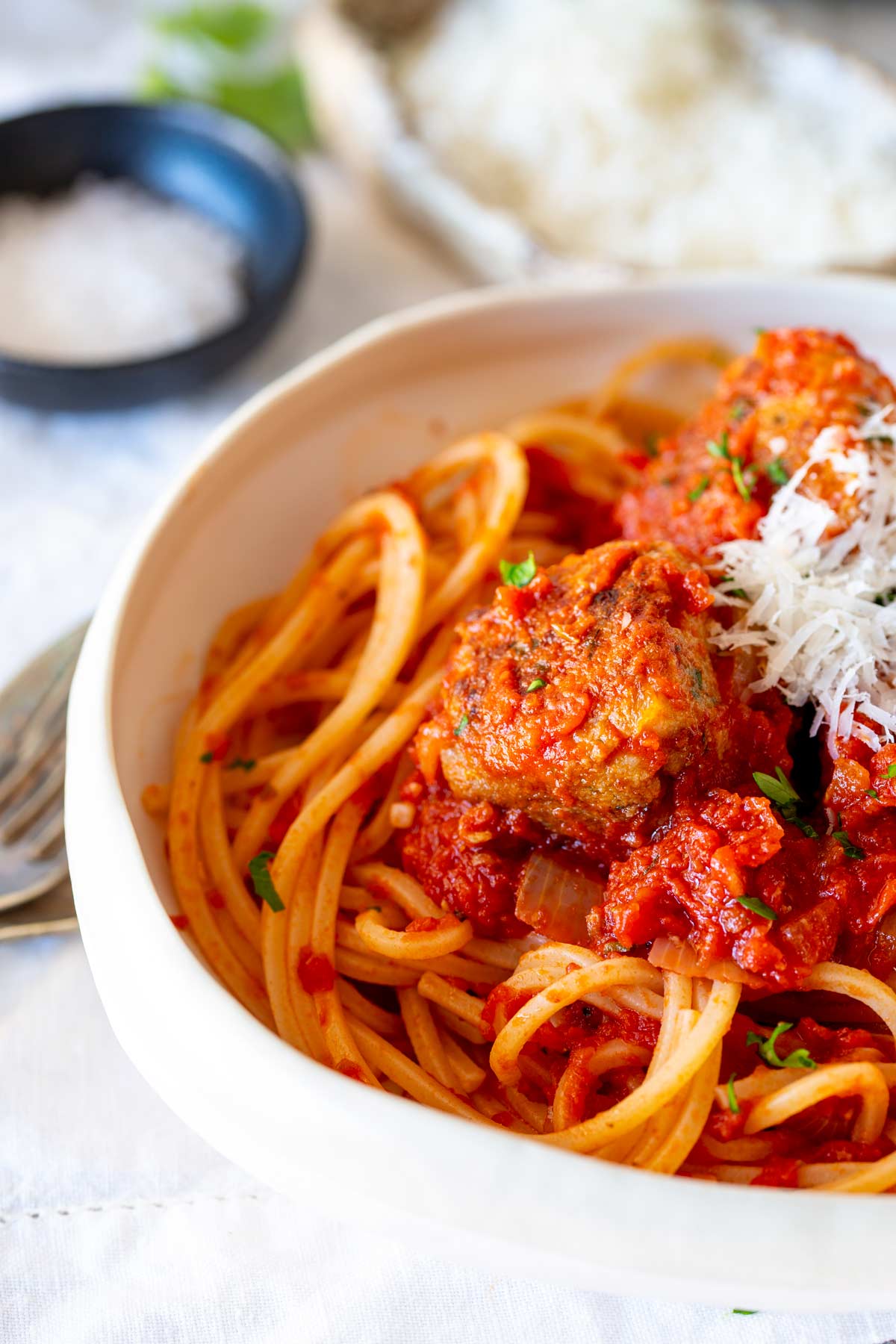 a hit bowl filled with spaghetti in a tomato sauce with meatballs on top