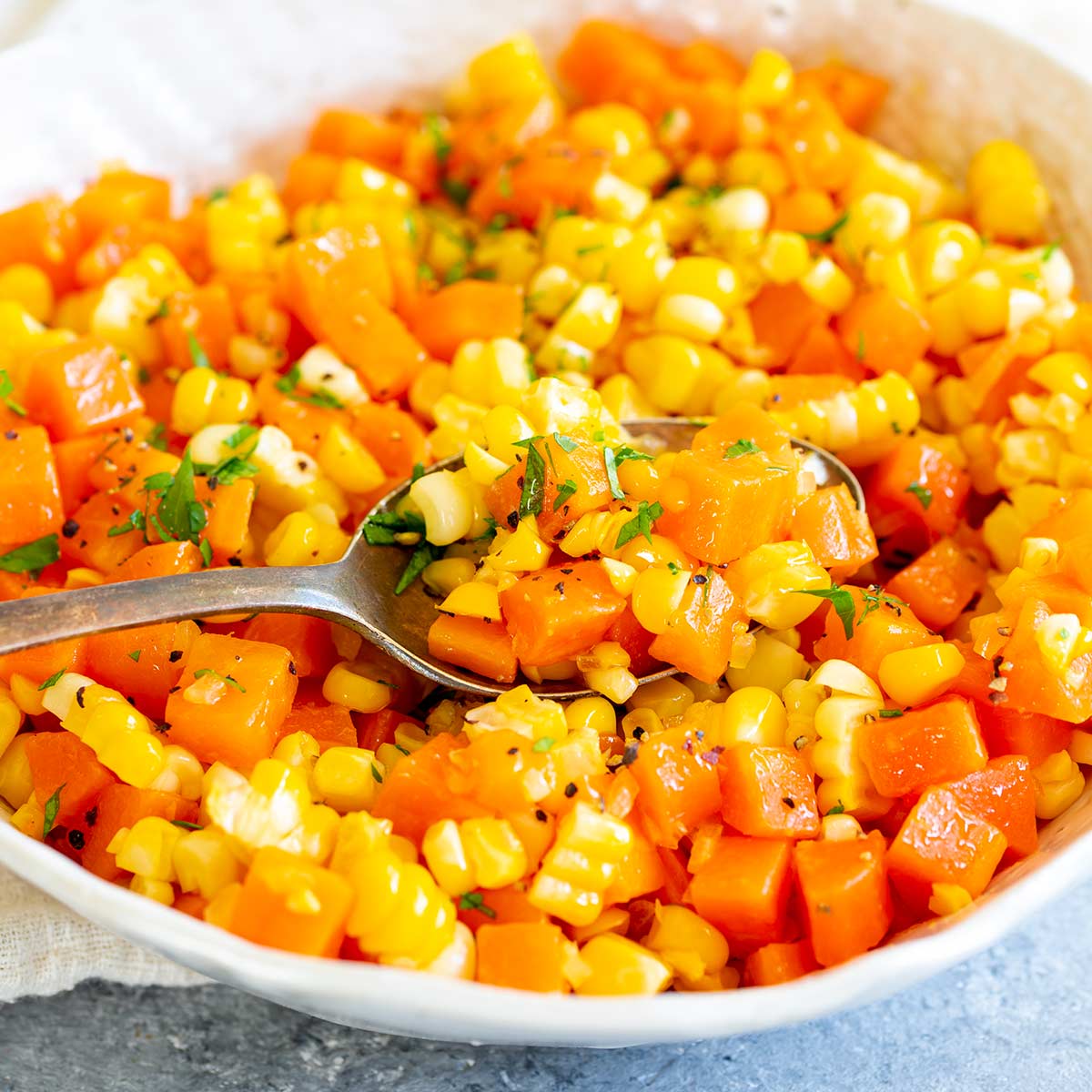 close up of a spoonful of chopped carrots and corn