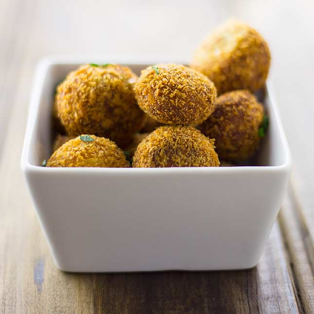 close up a white bowl of golden croquettes