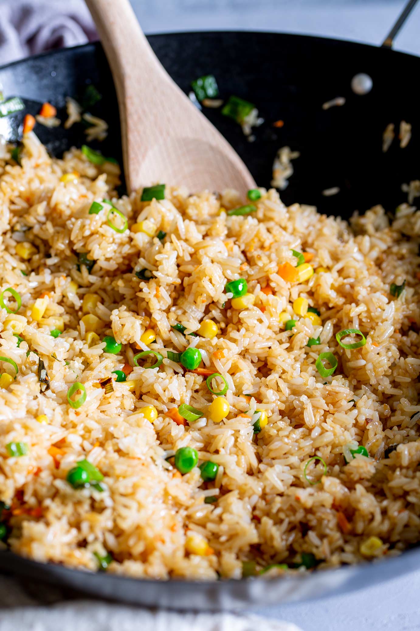 a spoon scooping rice from a wok