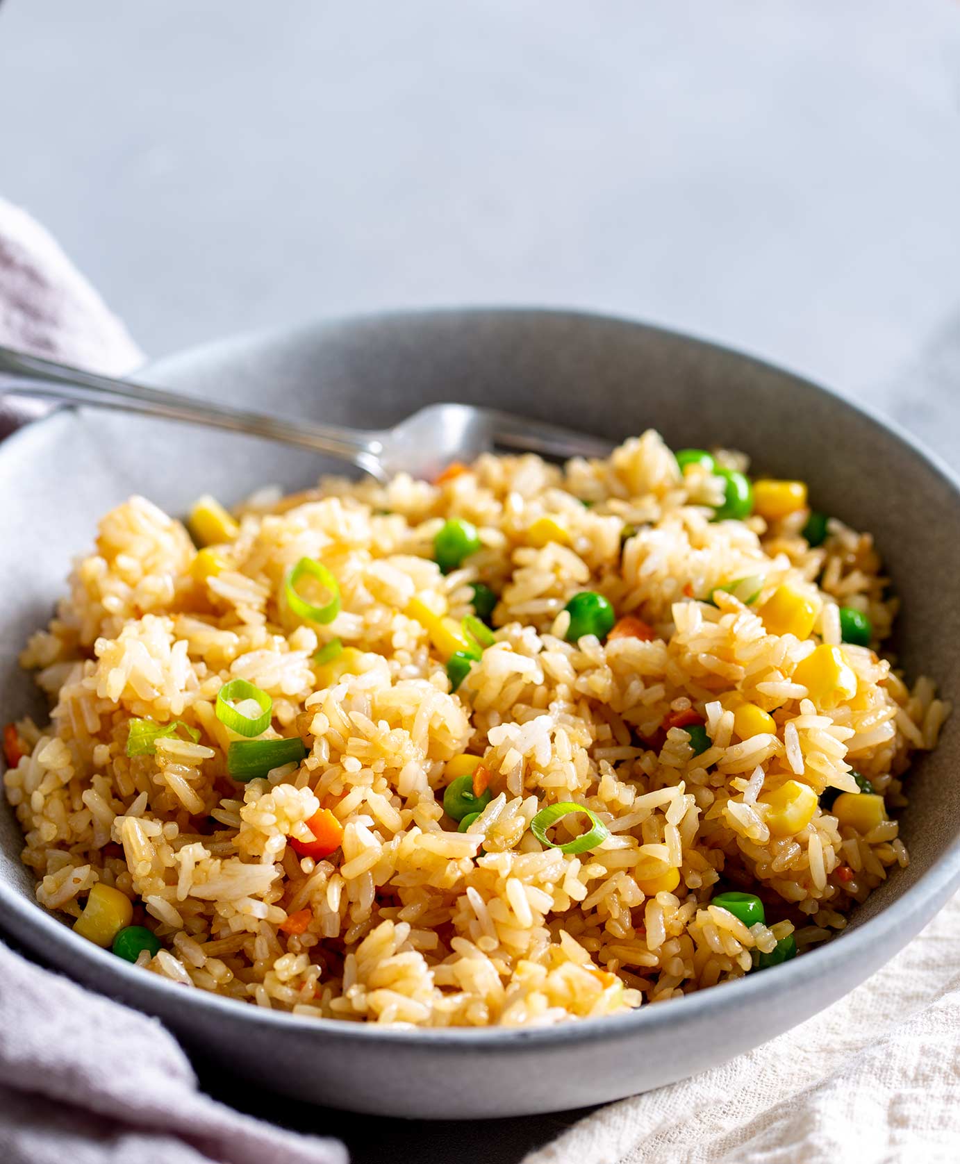 fried rice in a grey bowl with a fork at the back