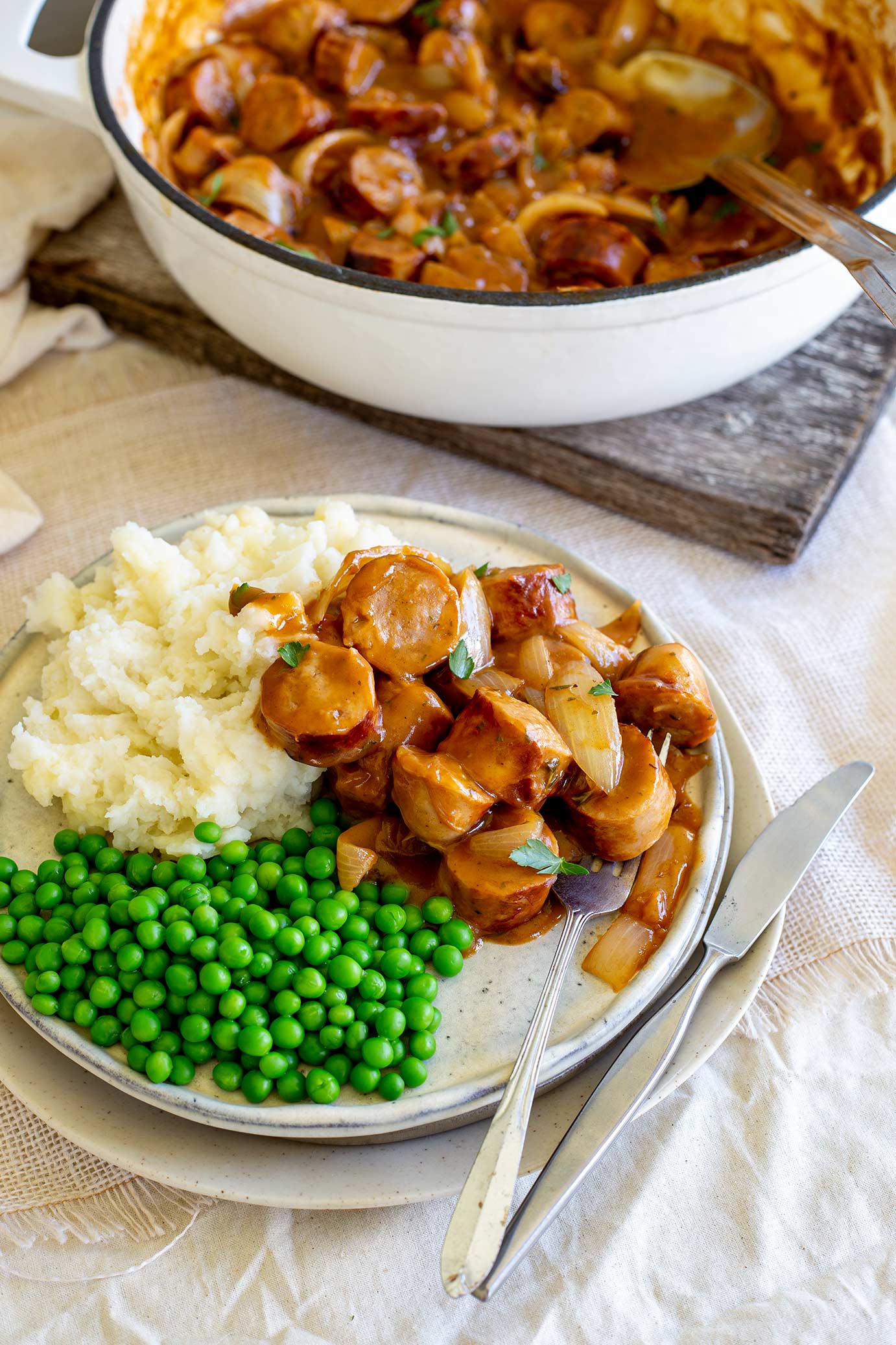 sausage casserole on a plate with mashed potatoes and peas