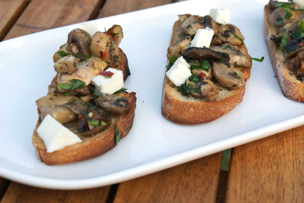Mushroom Bruschetta. Crisp crostini topped with mozzarella and garlic and parsley cooked mushrooms. A perfect appetizer, great with a glass of wine or a cold beer.