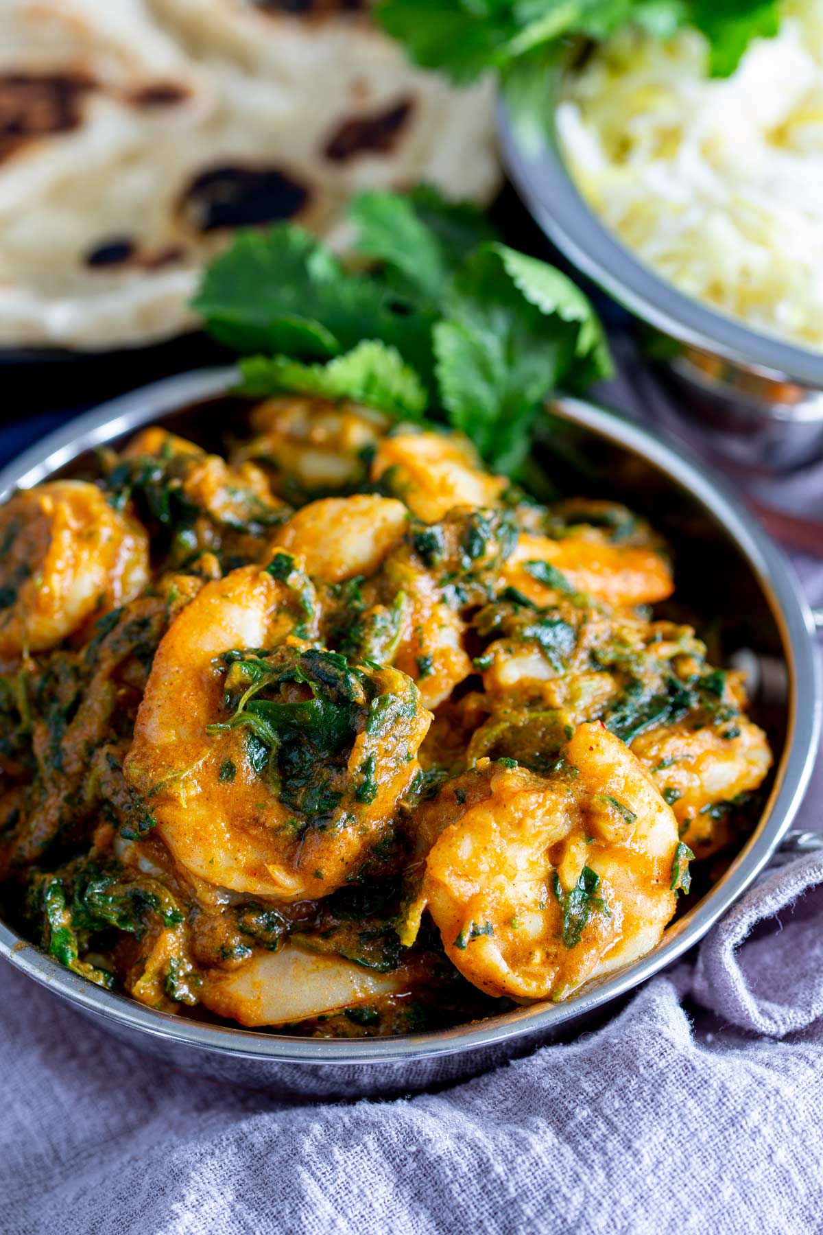 cooked shrimp saag in a small bowl on a grey napkin